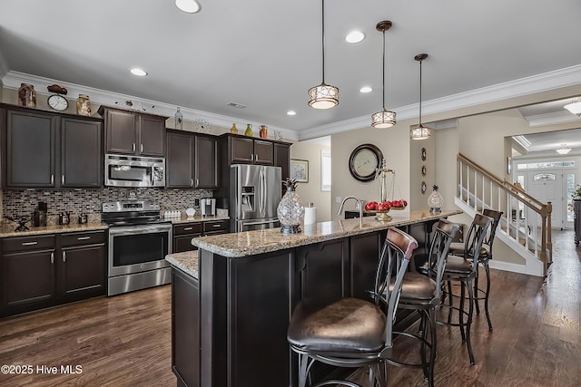 6509 Fawn Settle Dr, Wilmington, NC 28409 - kitchen with stainless steel appliances, a kitchen bar, dark wood-style flooring, ornamental molding, and light stone counters