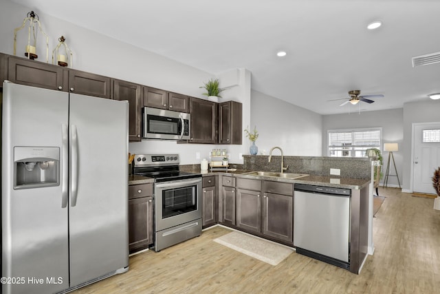 141 Beacon Woods Dr, Holly Ridge, NC 28445 - kitchen featuring appliances with stainless steel finishes, a sink, a peninsula, dark brown cabinetry, and light wood finished floors