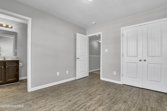 141 Beacon Woods Dr, Holly Ridge, NC 28445 - unfurnished bedroom featuring wood finished floors, baseboards, a sink, and a closet