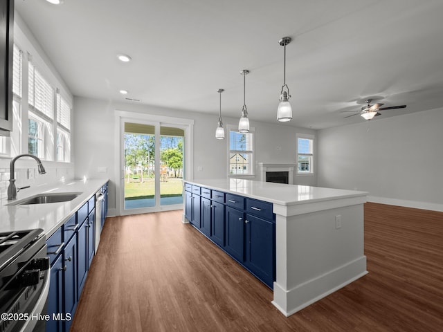 153 Ballantine Grove Ln, Newport, NC 28570 - kitchen with blue cabinets, a sink, stainless steel gas range, dark wood-type flooring, and a fireplace