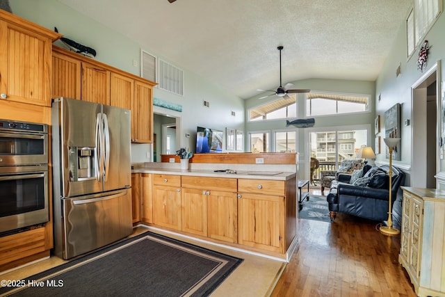 kitchen with light countertops, black electric cooktop, lofted ceiling, and visible vents