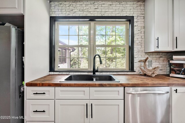 kitchen featuring wooden counters, appliances with stainless steel finishes, a sink, and plenty of natural light