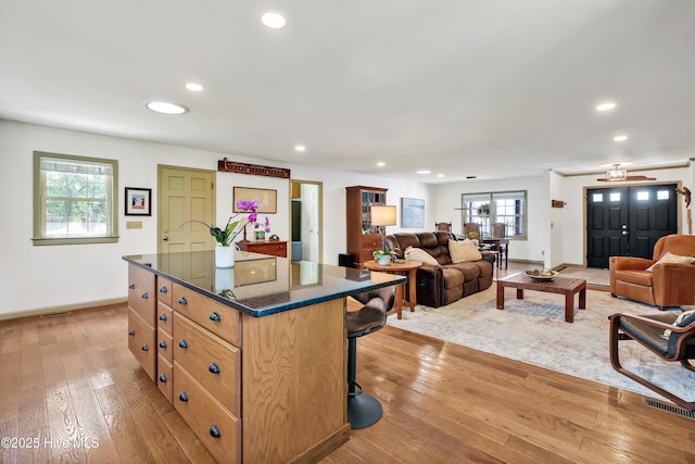 kitchen with baseboards, a kitchen island, recessed lighting, light wood finished floors, and open floor plan