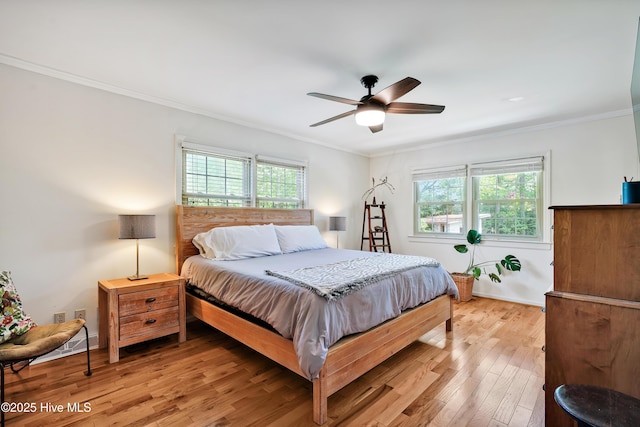 bedroom with multiple windows, ornamental molding, light wood-type flooring, ceiling fan, and baseboards