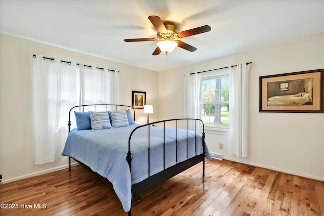 bedroom with light wood-type flooring, a ceiling fan, and baseboards