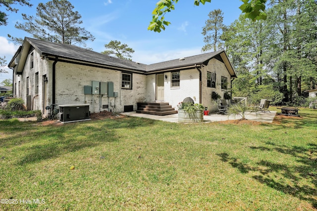 back of house with a fire pit, brick siding, a patio area, and a yard