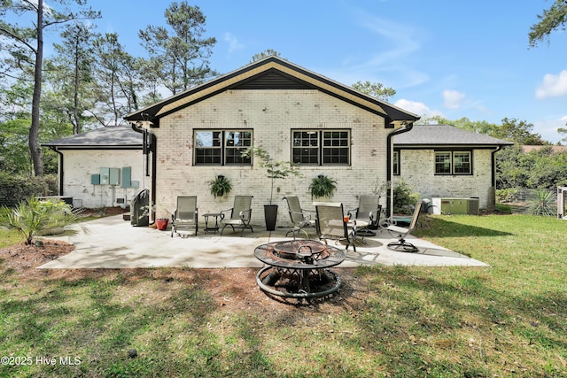 back of house with a fire pit, brick siding, a patio, and a yard