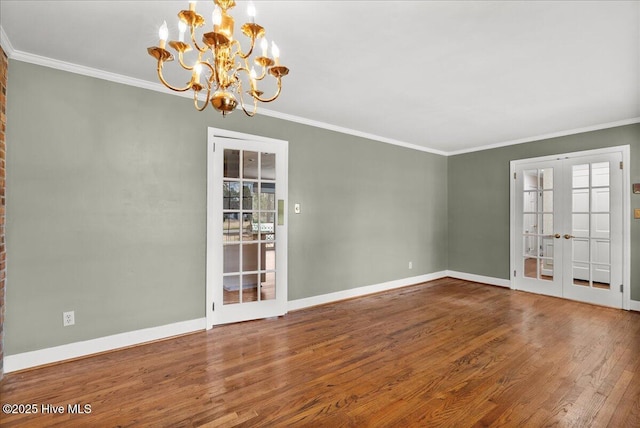 spare room with french doors, baseboards, a notable chandelier, wood finished floors, and ornamental molding
