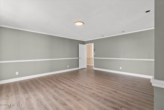 spare room with baseboards, crown molding, and wood finished floors