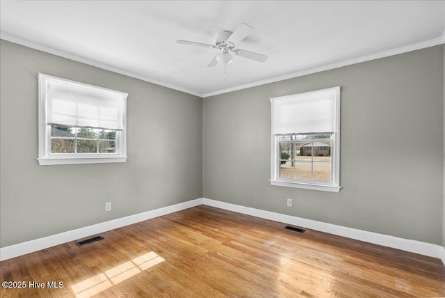 empty room with baseboards, ornamental molding, and visible vents