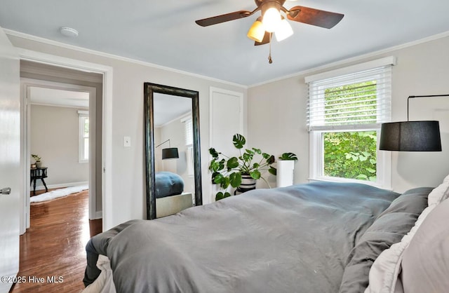 bedroom featuring wood finished floors, ornamental molding, multiple windows, baseboards, and ceiling fan