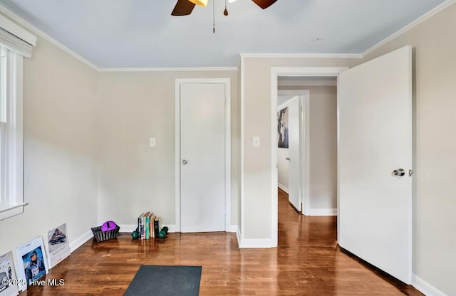 unfurnished bedroom featuring wood finished floors, ornamental molding, baseboards, and a ceiling fan