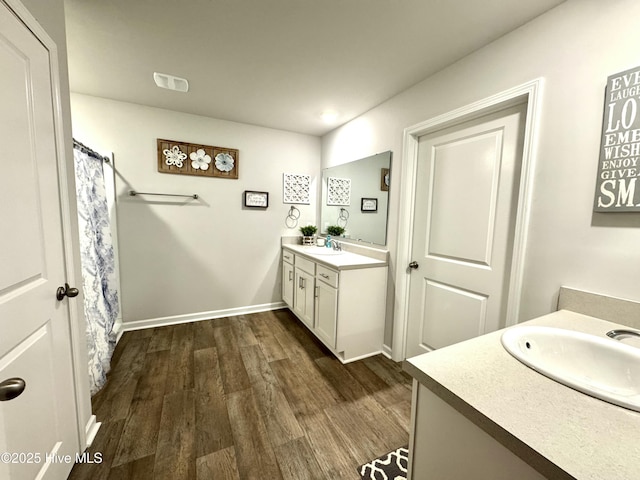 full bathroom featuring two vanities, wood finished floors, a sink, and visible vents