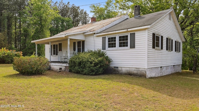 view of front facade featuring a front yard, crawl space, a chimney, and covered porch