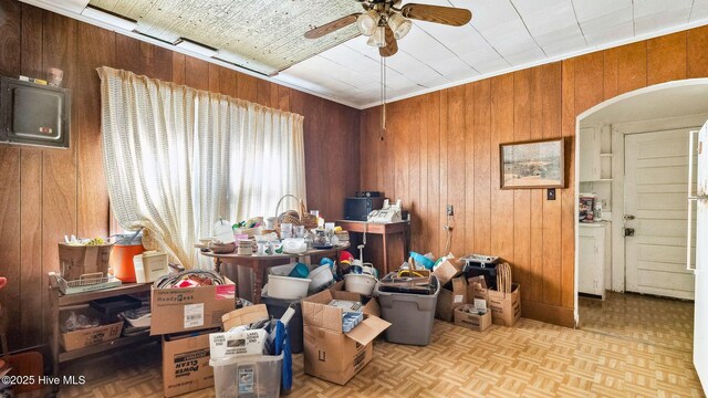 miscellaneous room featuring wooden walls, arched walkways, and ceiling fan