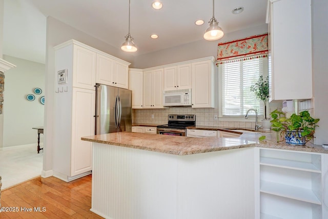 kitchen featuring appliances with stainless steel finishes, a sink, light wood-style flooring, backsplash, and light stone countertops