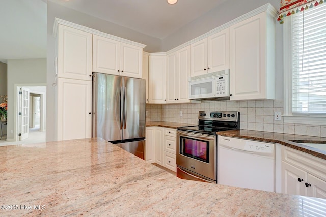 kitchen featuring stainless steel appliances, dark stone counters, tasteful backsplash, and white cabinetry