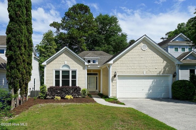 view of front of property featuring an attached garage, concrete driveway, cooling unit, and a front lawn