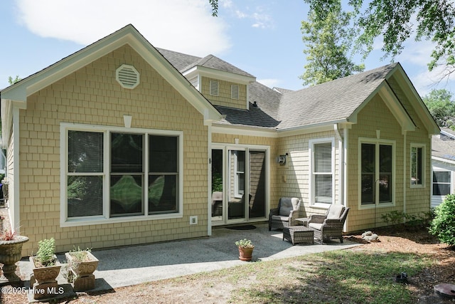 rear view of property featuring a shingled roof and a patio area