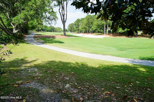 view of community with a lawn, view of golf course, and view of wooded area