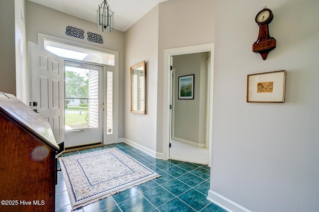 foyer featuring baseboards and dark tile patterned flooring