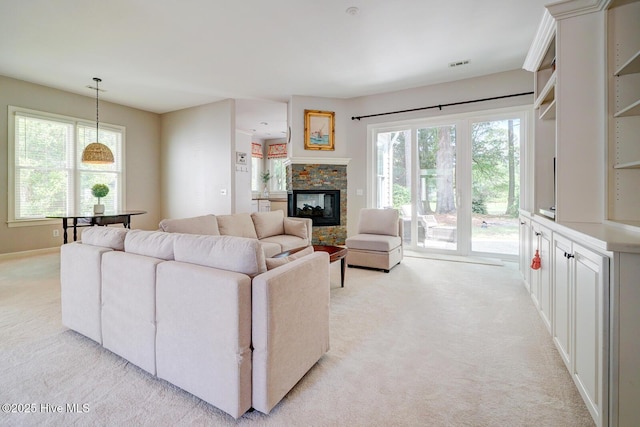 living area featuring light colored carpet, a fireplace, and baseboards