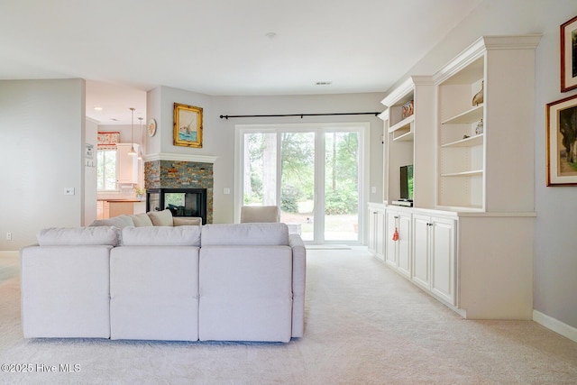 living room with light colored carpet, plenty of natural light, and a stone fireplace