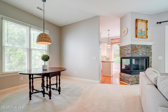 dining room featuring light colored carpet, plenty of natural light, and baseboards