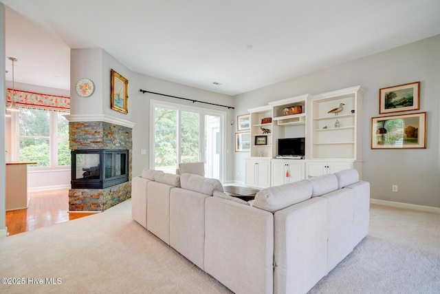 living area with light colored carpet, baseboards, and a stone fireplace