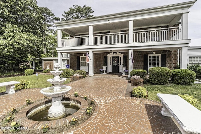 view of front facade with brick siding and a balcony