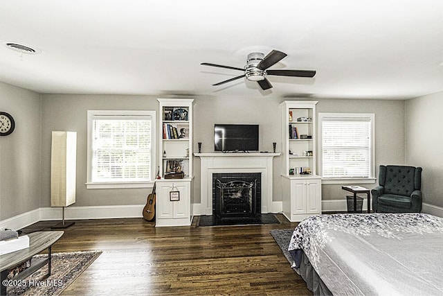 300 Moye Ave NW, Wilson, NC 27893 - bedroom with multiple windows, a fireplace with flush hearth, dark wood-style floors, and a ceiling fan