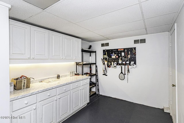 interior space with white cabinets, a paneled ceiling, and visible vents