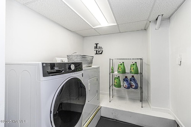clothes washing area with baseboards, washer and dryer, and laundry area