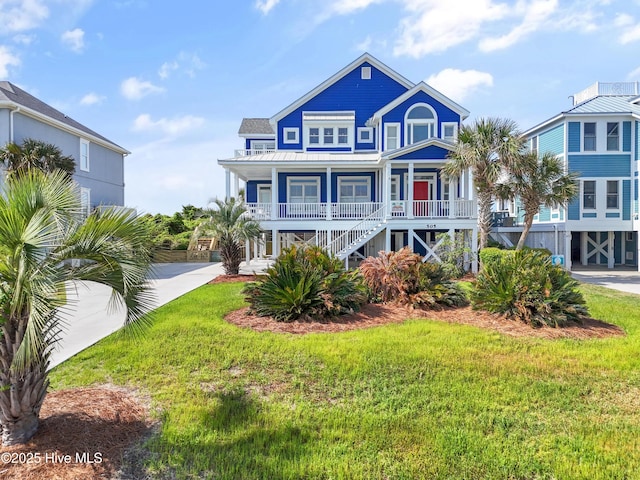 505 Caswell Beach Rd, Caswell Beach, NC 28465 - view of front of house with covered porch, a front yard, a standing seam roof, metal roof, and stairway