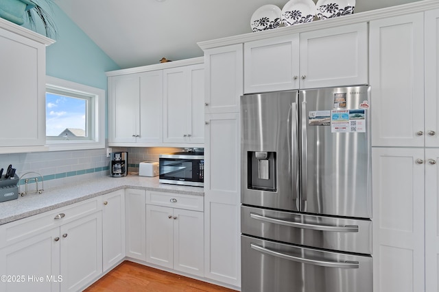 505 Caswell Beach Rd, Caswell Beach, NC 28465 - kitchen with white cabinets, stainless steel appliances, vaulted ceiling, and tasteful backsplash