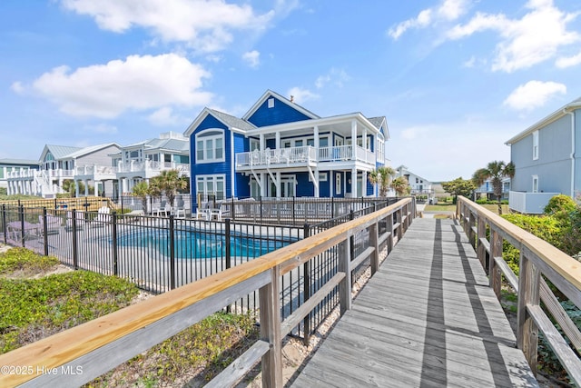 505 Caswell Beach Rd, Caswell Beach, NC 28465 - back of property with fence, a balcony, a patio, a community pool, and a residential view