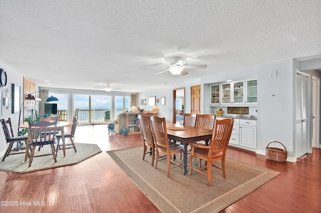 dining area featuring ceiling fan, dark wood-style flooring, a textured ceiling, and baseboards