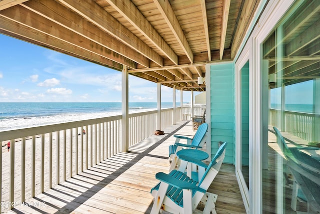 wooden terrace with view of water and beach