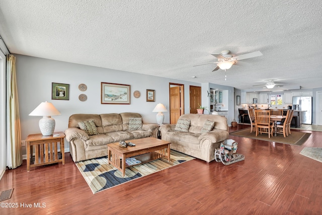 living room featuring ceiling fan, a textured ceiling, and wood finished floors