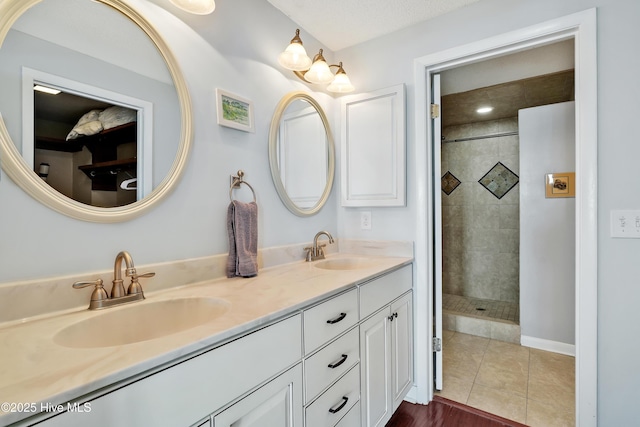 full bath with double vanity, a tile shower, and tile patterned floors