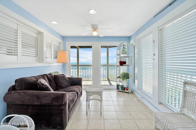 living area featuring a ceiling fan, a water view, light tile patterned flooring, a textured ceiling, and recessed lighting