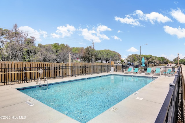 community pool with fence and a patio area
