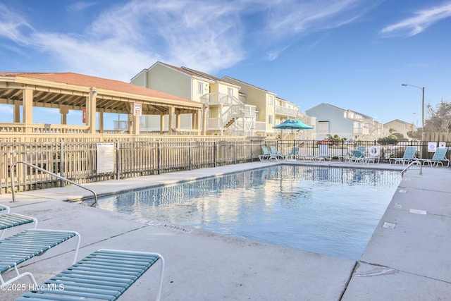 community pool featuring fence, a residential view, and a patio