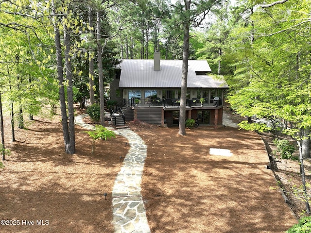 view of front of house with a chimney, metal roof, and stairs