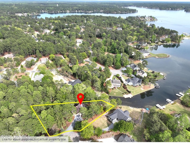 aerial overview of property's location with a nearby body of water, property parcel outlined, and a heavily wooded area