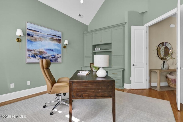 office area with baseboards, wood finished floors, visible vents, and high vaulted ceiling
