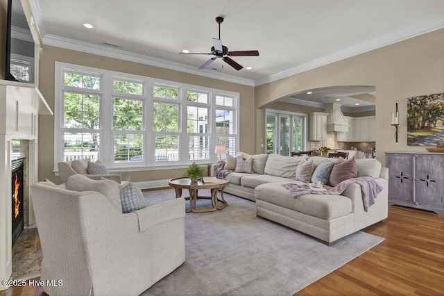 living area with arched walkways, ceiling fan, wood finished floors, and a wealth of natural light