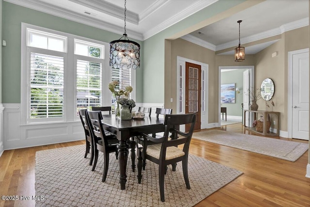 dining space featuring visible vents, wainscoting, a notable chandelier, ornamental molding, and light wood-style flooring