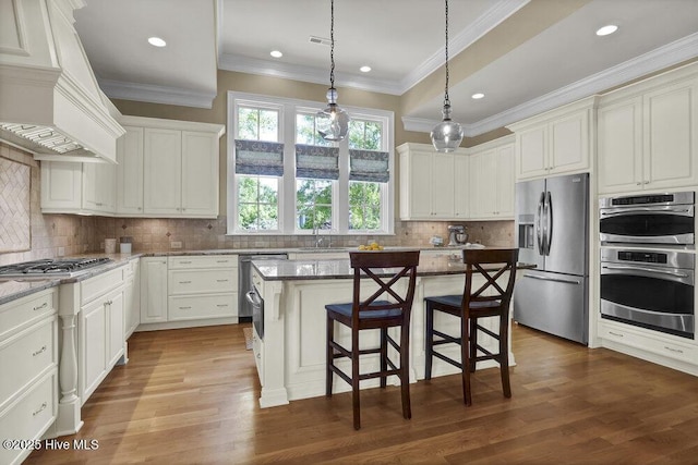 kitchen featuring decorative backsplash, a kitchen bar, appliances with stainless steel finishes, a sink, and custom range hood
