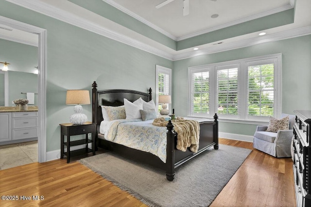 bedroom featuring crown molding, ceiling fan, light wood-style flooring, baseboards, and ensuite bathroom